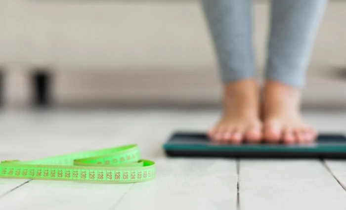 Woman on scale with measuring tape in front